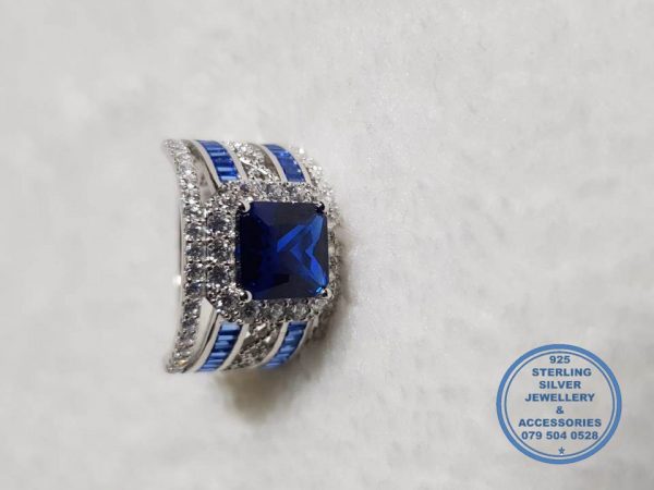 925 Sterling Silver Ring Showstopper Of Note. Large Halo Blue Square in middle with side curl band detail and 2 rows of blue baguettes down sides with clear cubic detail. Must Have